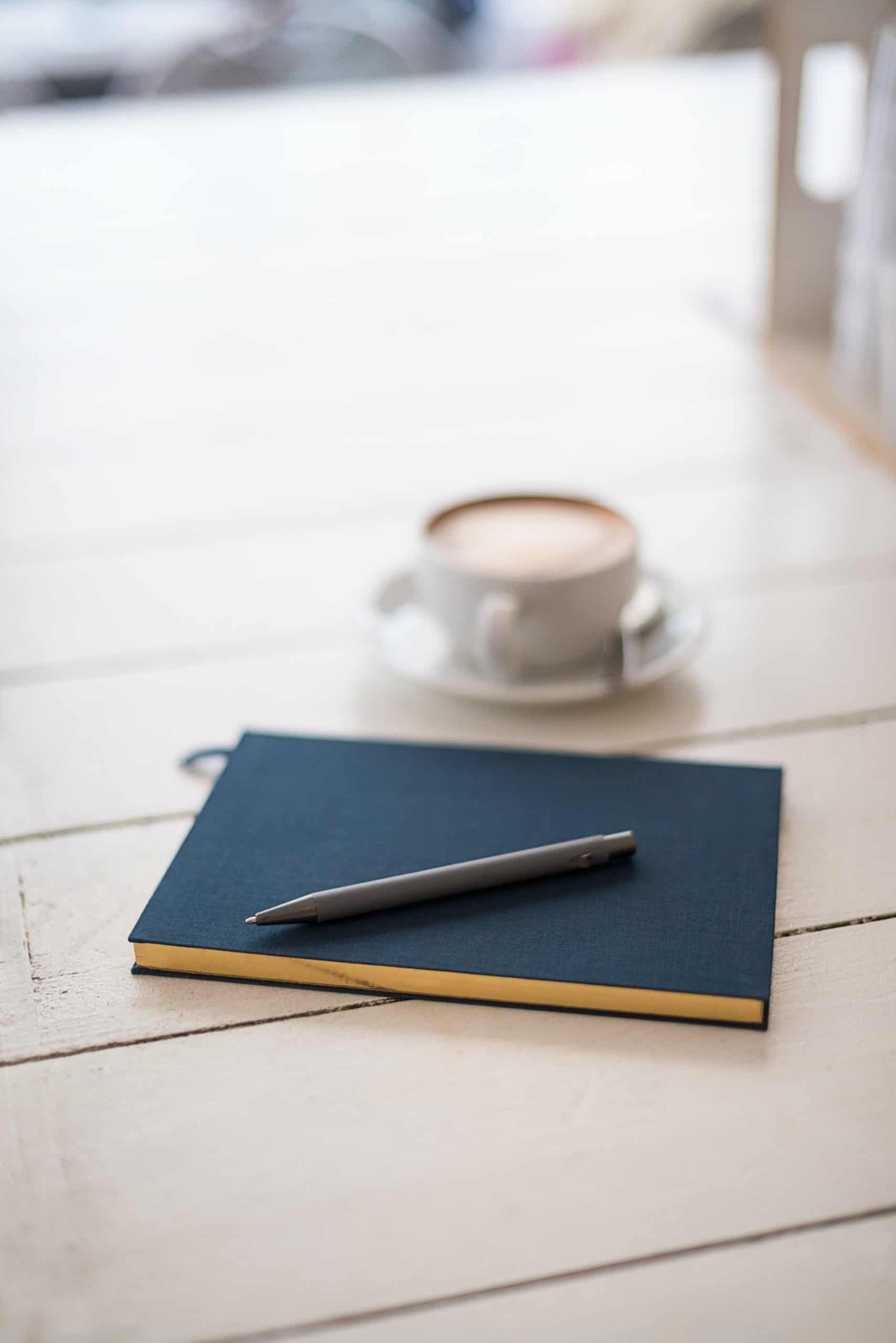 Notizbuch und Stift auf einem weißen Tisch mit verschwommenen Hintergrund