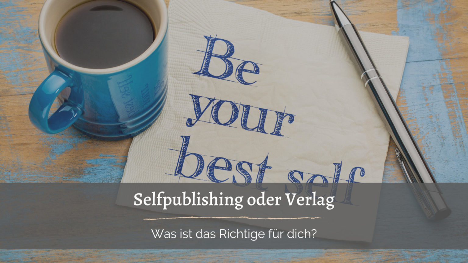 Foto von einem Holztisch, auf dem noch blaue Farbreste zu erkennen sind. Auf dem Tisch steht eine blaue Kaffeetasse, liegt ein silberner Kugelschreiber und eine Serviette mit dem Text: Be your best self. Geschrieben in blauer Schrift. Zusätzlicher Text in einem dunkelbraunen Kasten. Selfpublishing oder Verlag - Was ist das Richtige für dich?